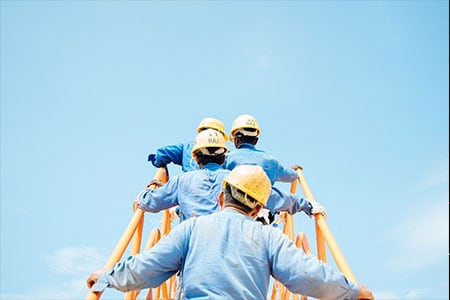 workers wearing hard hats climbing a staircase