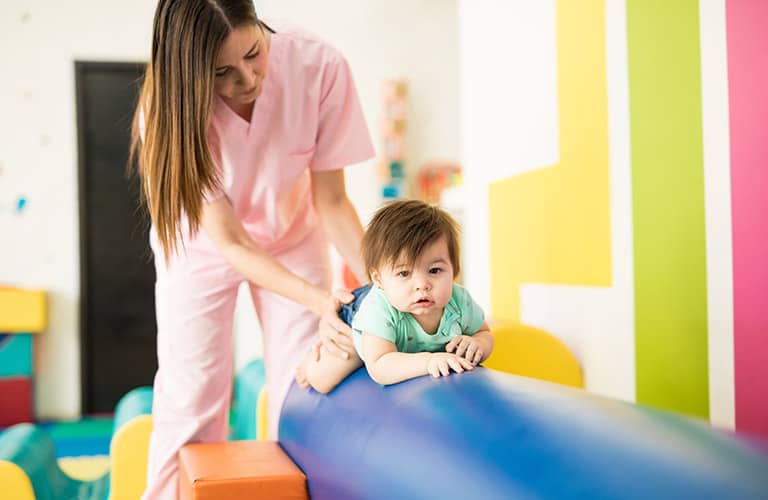 physical therapist with toddler on pediatric equipment